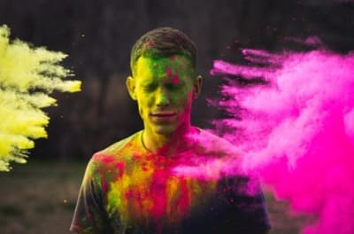 man with color bursts around him from a color run to symbolize joy
