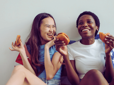 two young women smiling and eating pizza with not a care in the world about calorie counting